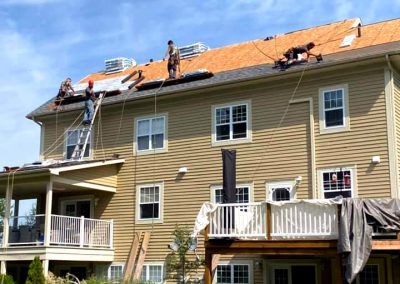 Un groupe de personnes travaille sur le toit d'une grande maison.