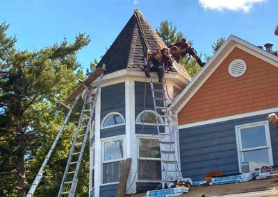 Un groupe d'hommes travaillent sur le toit d'une maison.