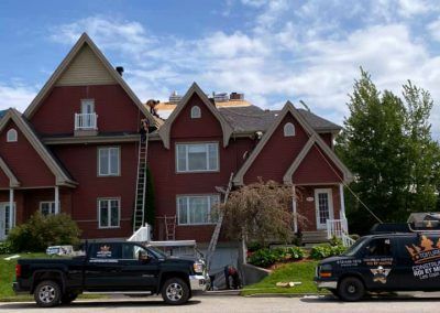Deux camions sont garés devant une grande maison rouge