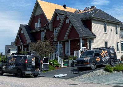 Deux camionnettes sont garées devant une maison en cours de rénovation.