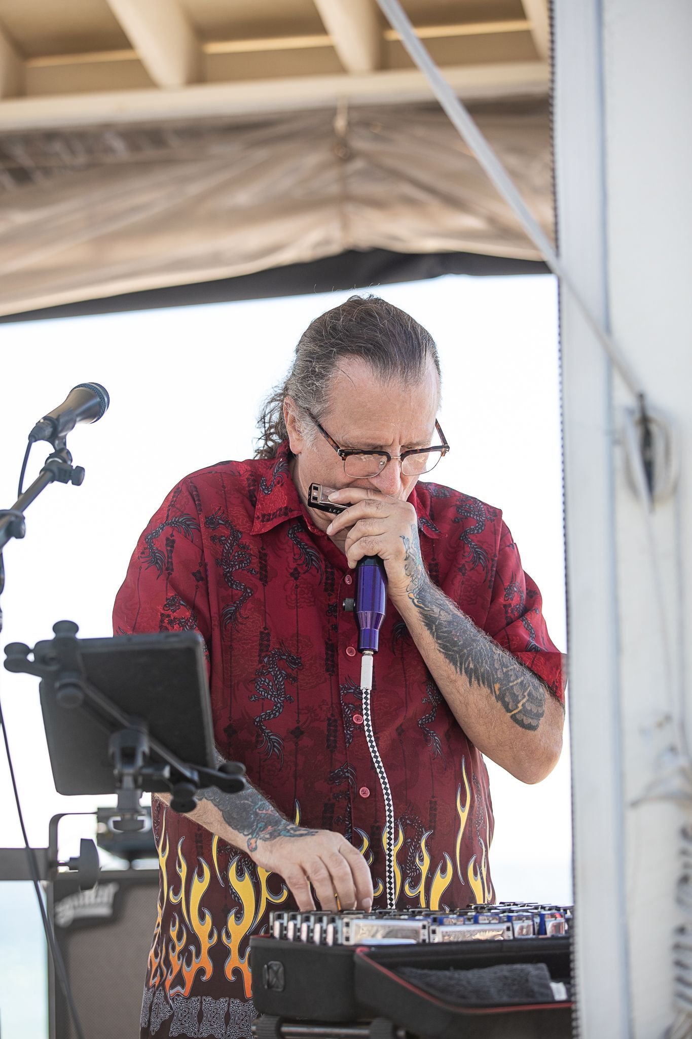 Musician in red shirt singing into a microphone on the Coastal Orange Beach outdoor stage