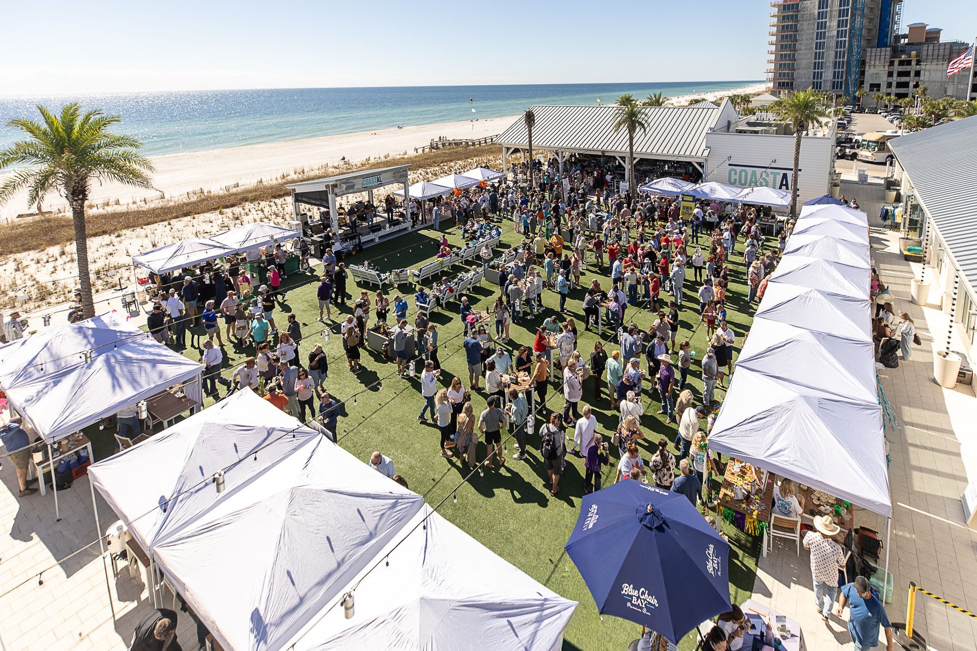 Gumbo Fest event at Coastal orange Beach on the green space, with white tents and a city skyline nearby