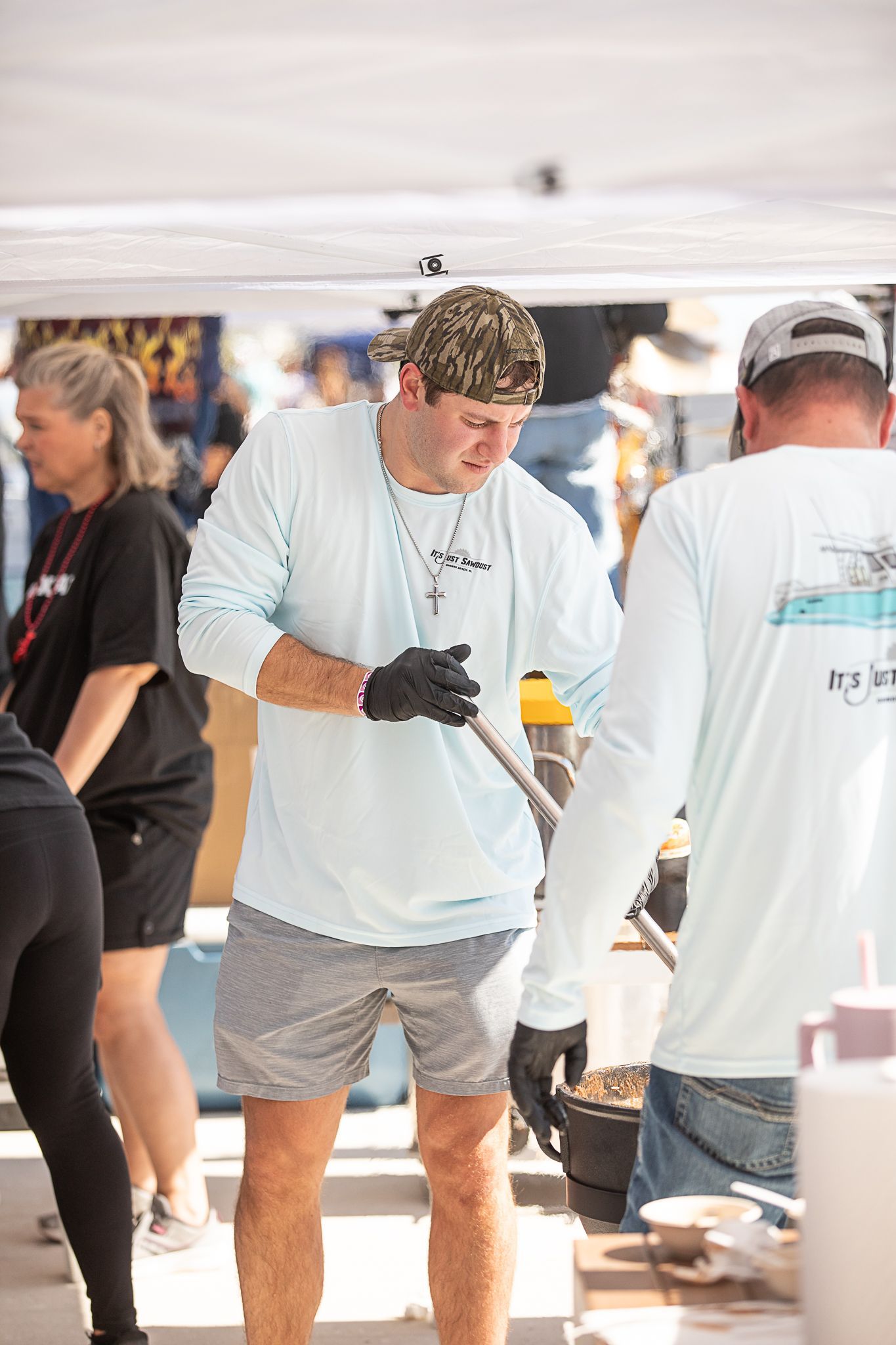 Man in white long-sleeve shirt stirring a big pot of gumbo at Coastal Orange Beach