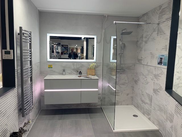 Une salle de bain avec lavabo, miroir et douche à l'italienne.