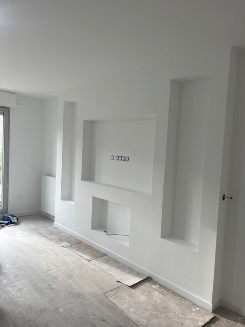 Un salon avec des murs blancs et une télévision fixée au mur.