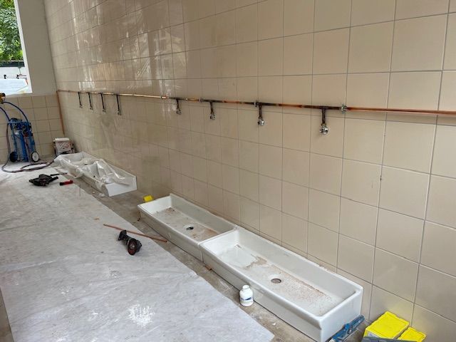 Une salle de bain avec un lavabo et des robinets au mur.