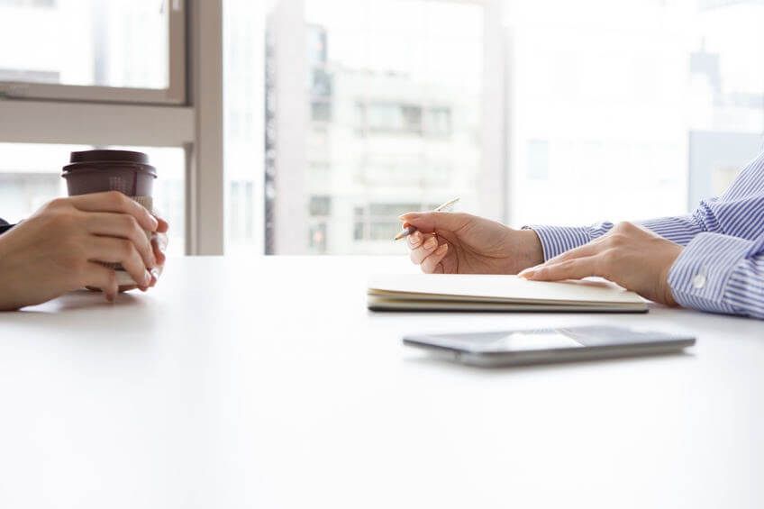 An interview being held over a white table, only showing the interviewer and interviewees hands