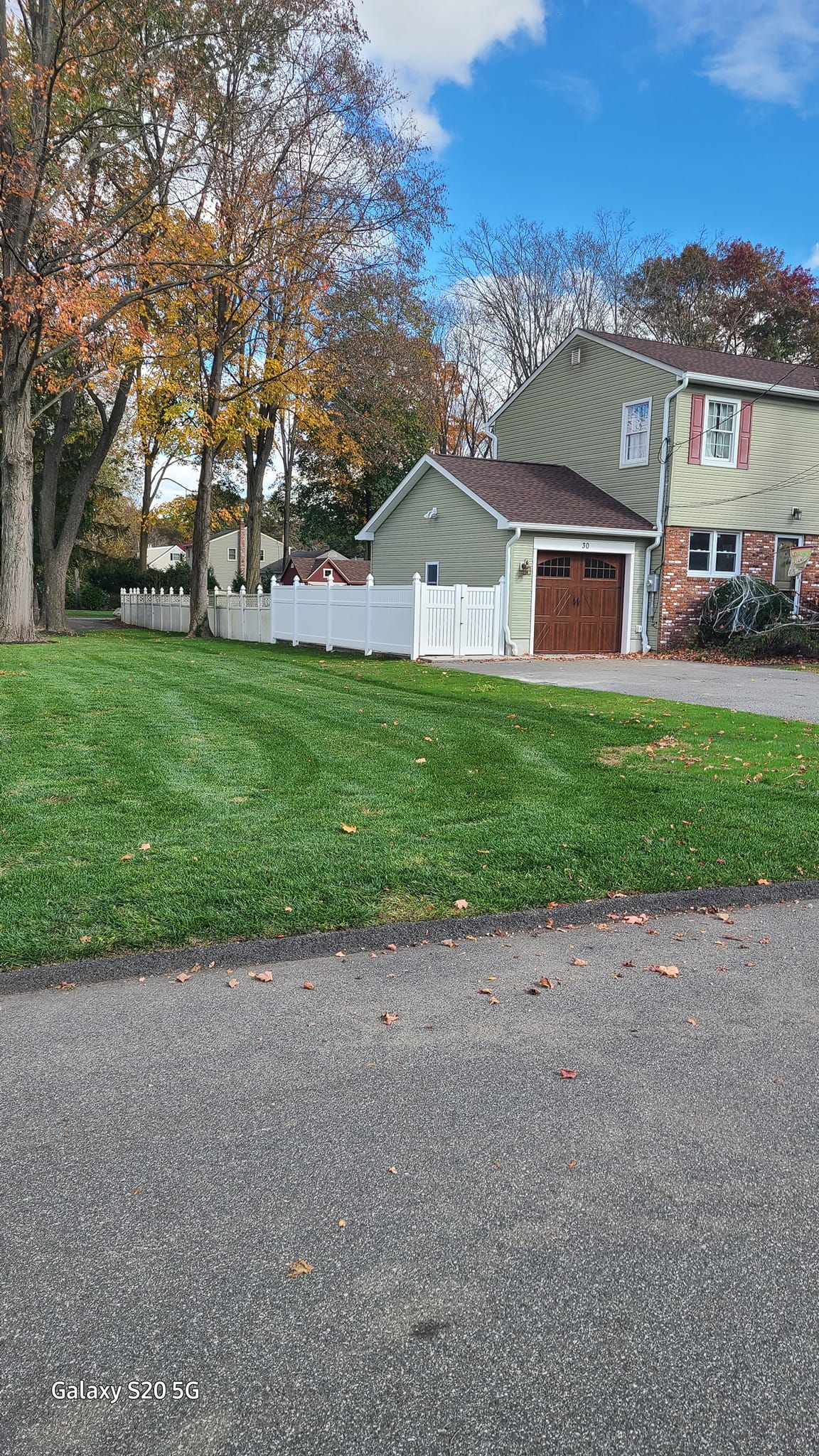 A house with a large lawn and a driveway in front of it.