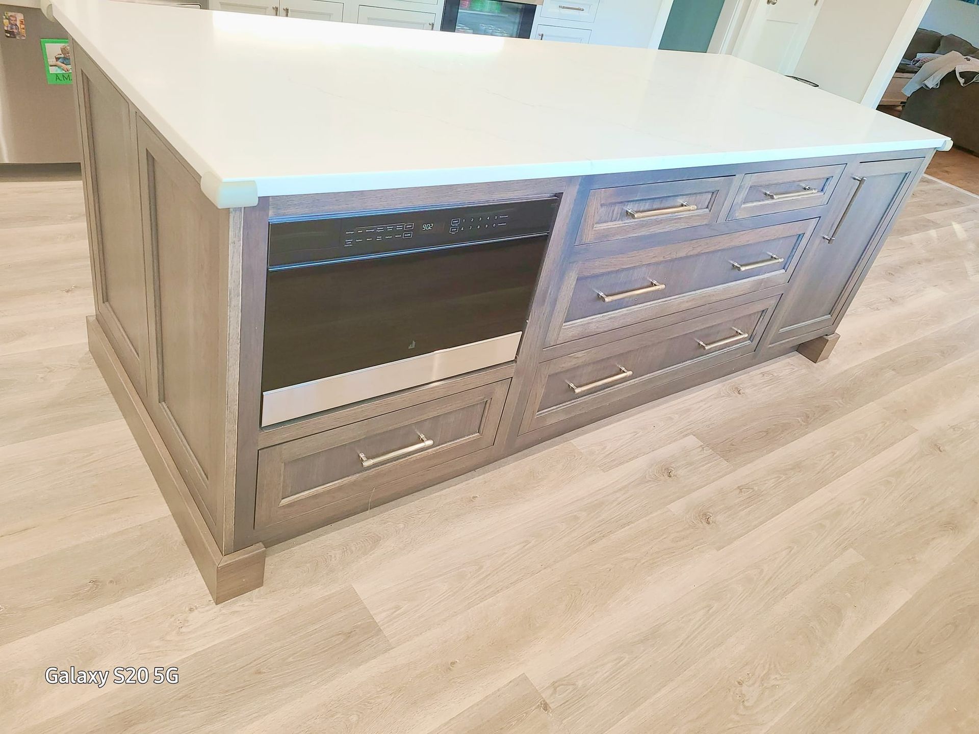 A kitchen island with a white counter top and drawers.