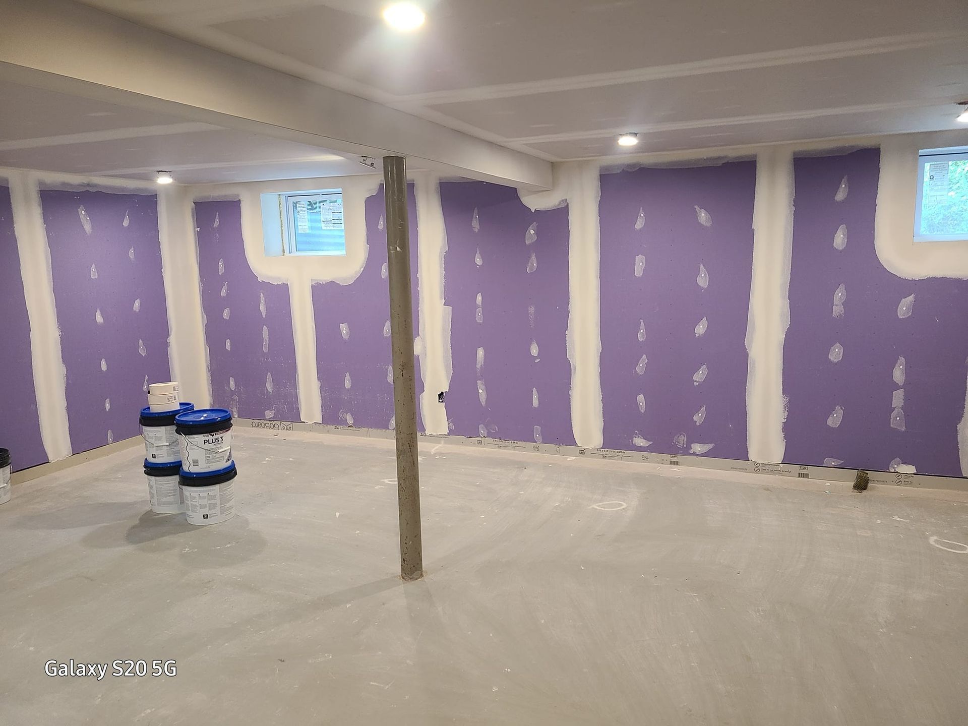 A basement with purple walls and white trim is being painted.