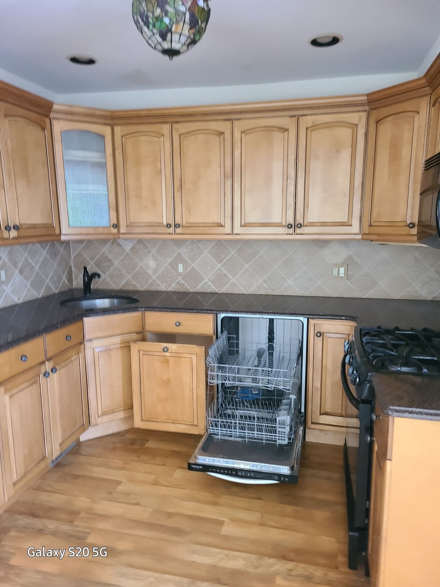 A kitchen with wooden cabinets and a dishwasher open