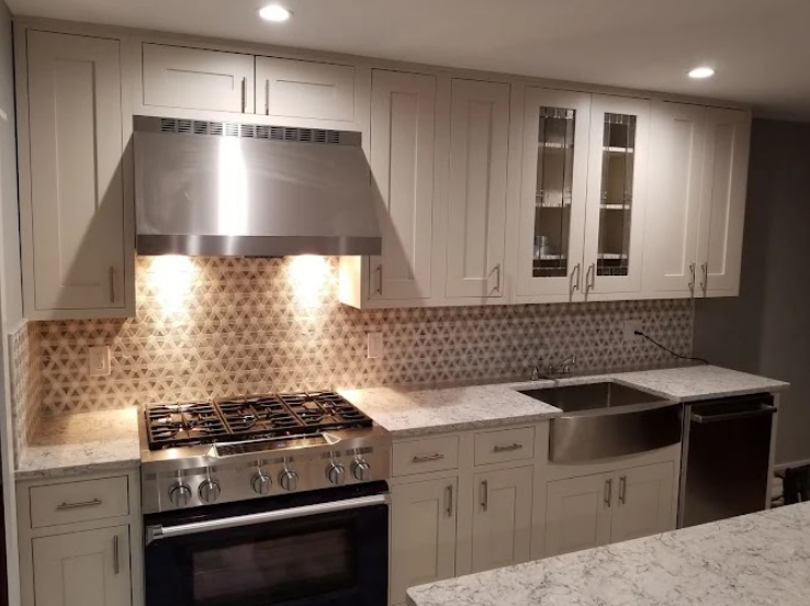 A modern kitchen with white cabinets, a stainless steel range hood