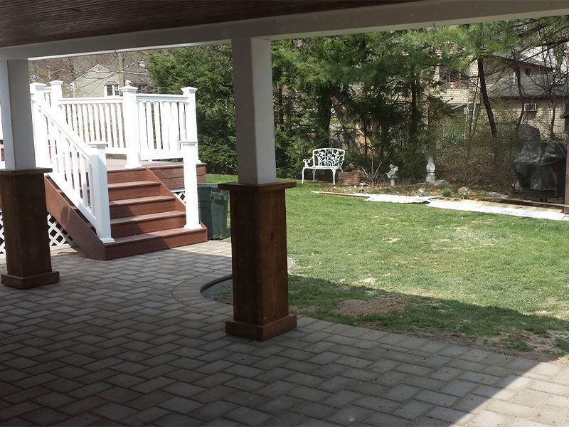 A patio with stairs leading up to a white deck