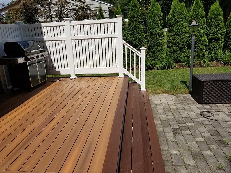 A wooden deck with a white fence and a grill