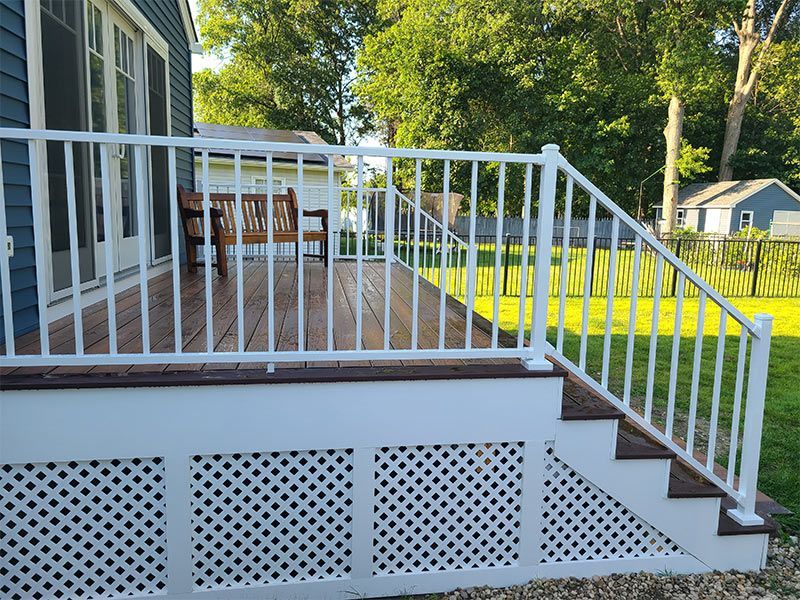 A deck with a white railing and stairs next to a house.