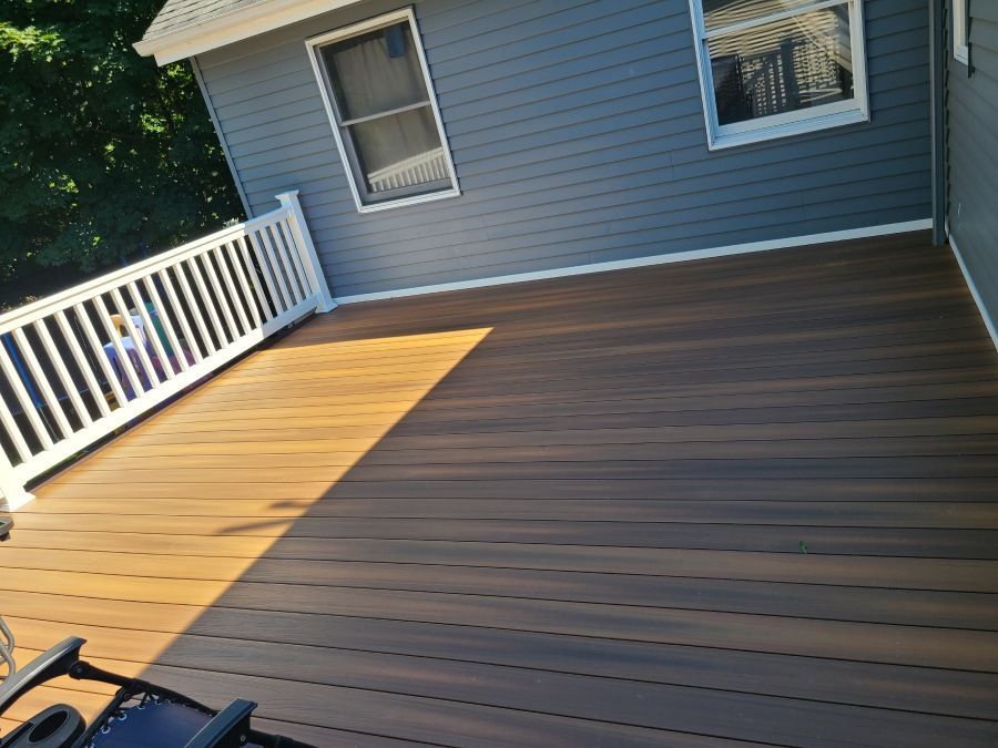 A wooden deck with a white railing in front of a house