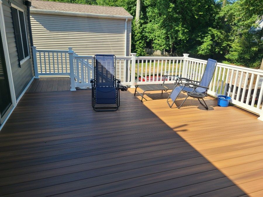 A wooden deck with chairs and a white railing