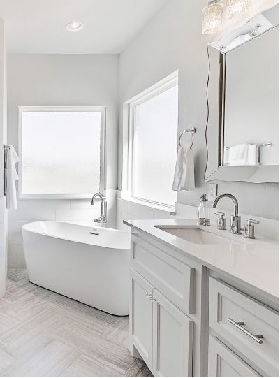 A bathroom with a tub , sink , mirror and window.