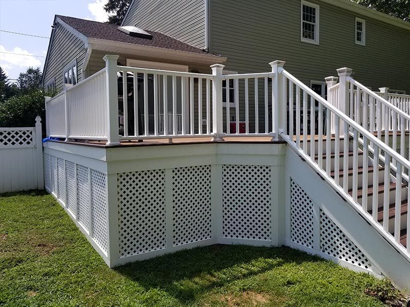 A white deck with stairs leading up to it in front of a house.
