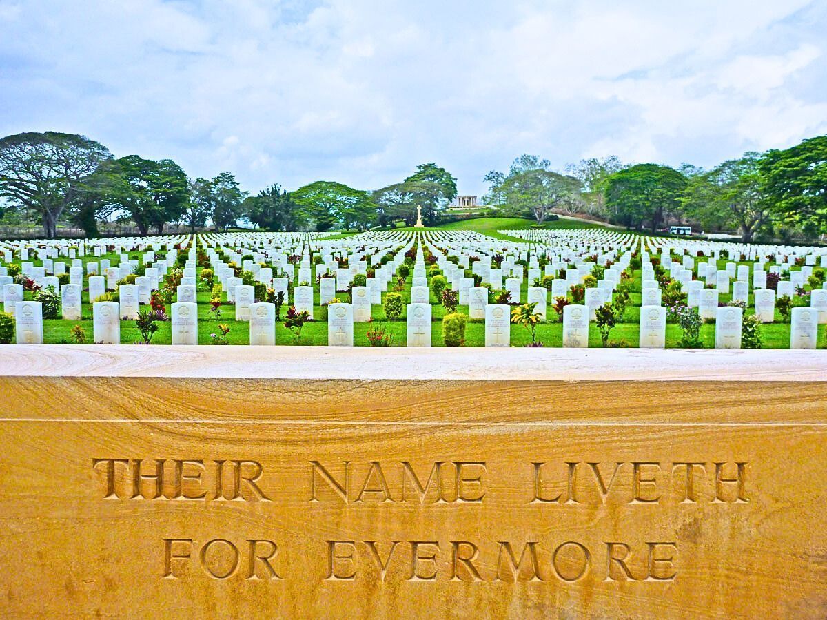The Bomana War Cemetery in Port Moresby with white headstones, green grass and blue sky.