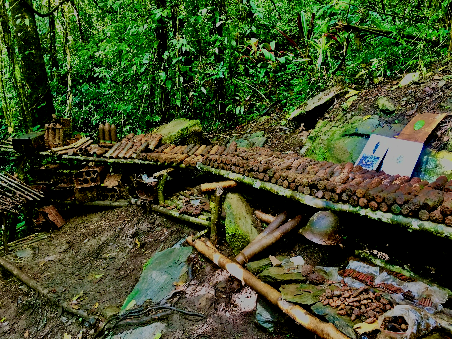 Kokoda Track hikers with backpacks wade through a shallow, rocky stream in a lush green Papua New Guinea jungle.