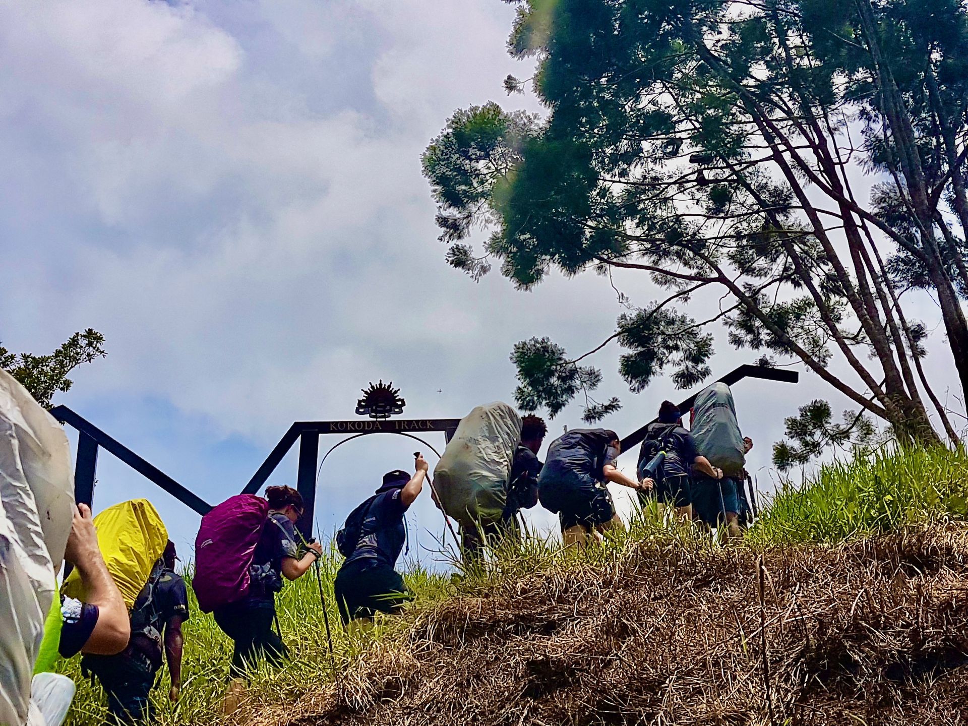 Image depicts trekkers ascending and reaching the Kokoda Trail arches at Owers Corner. Finishing the Kokoda Track.