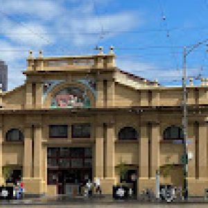 Picture of the front of the Queen Victoria Market which is a cream coloured building.