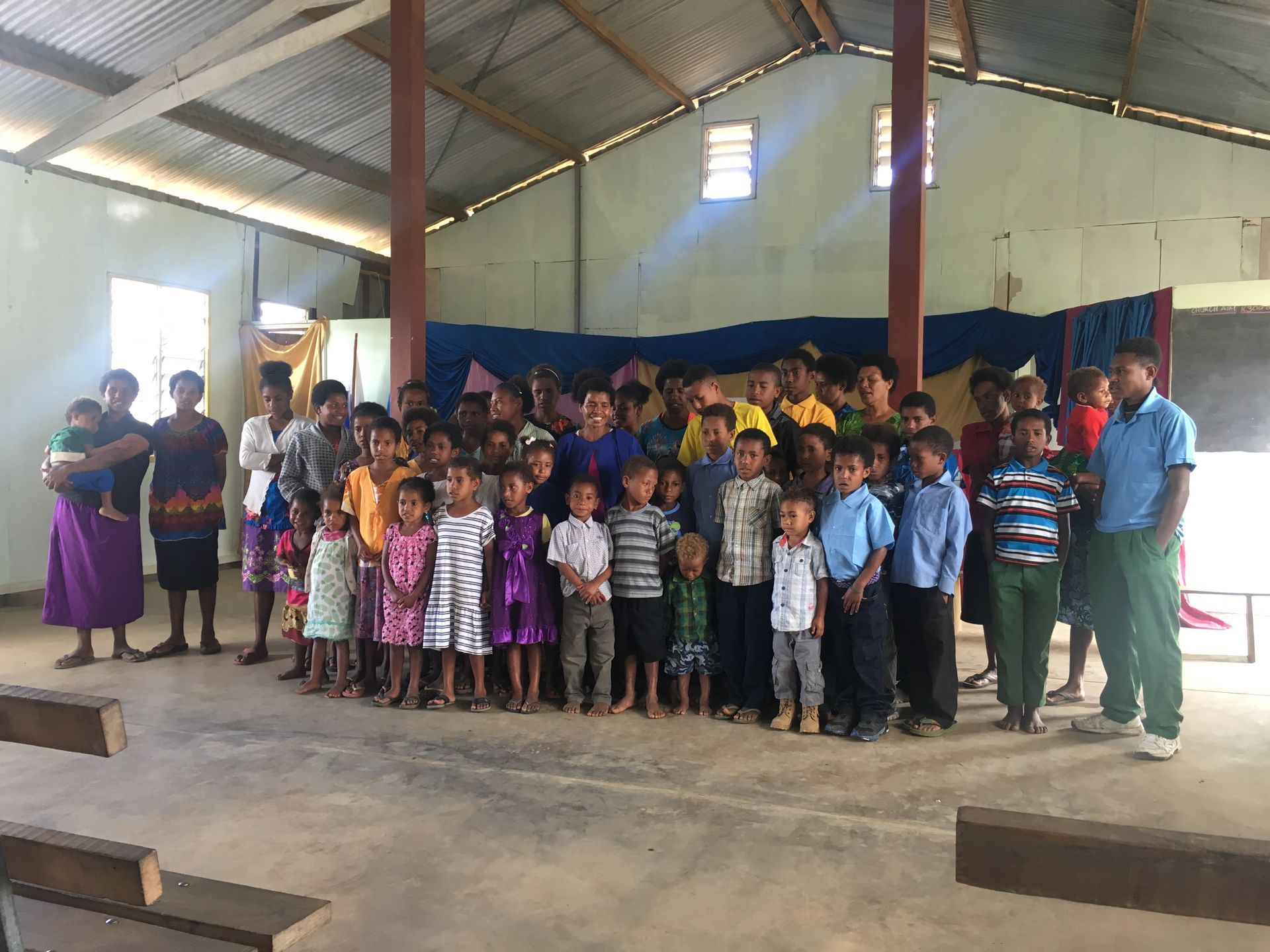 Image depicts the inside of a church at Kagi village with a group of worshipers singing with their congregation.  