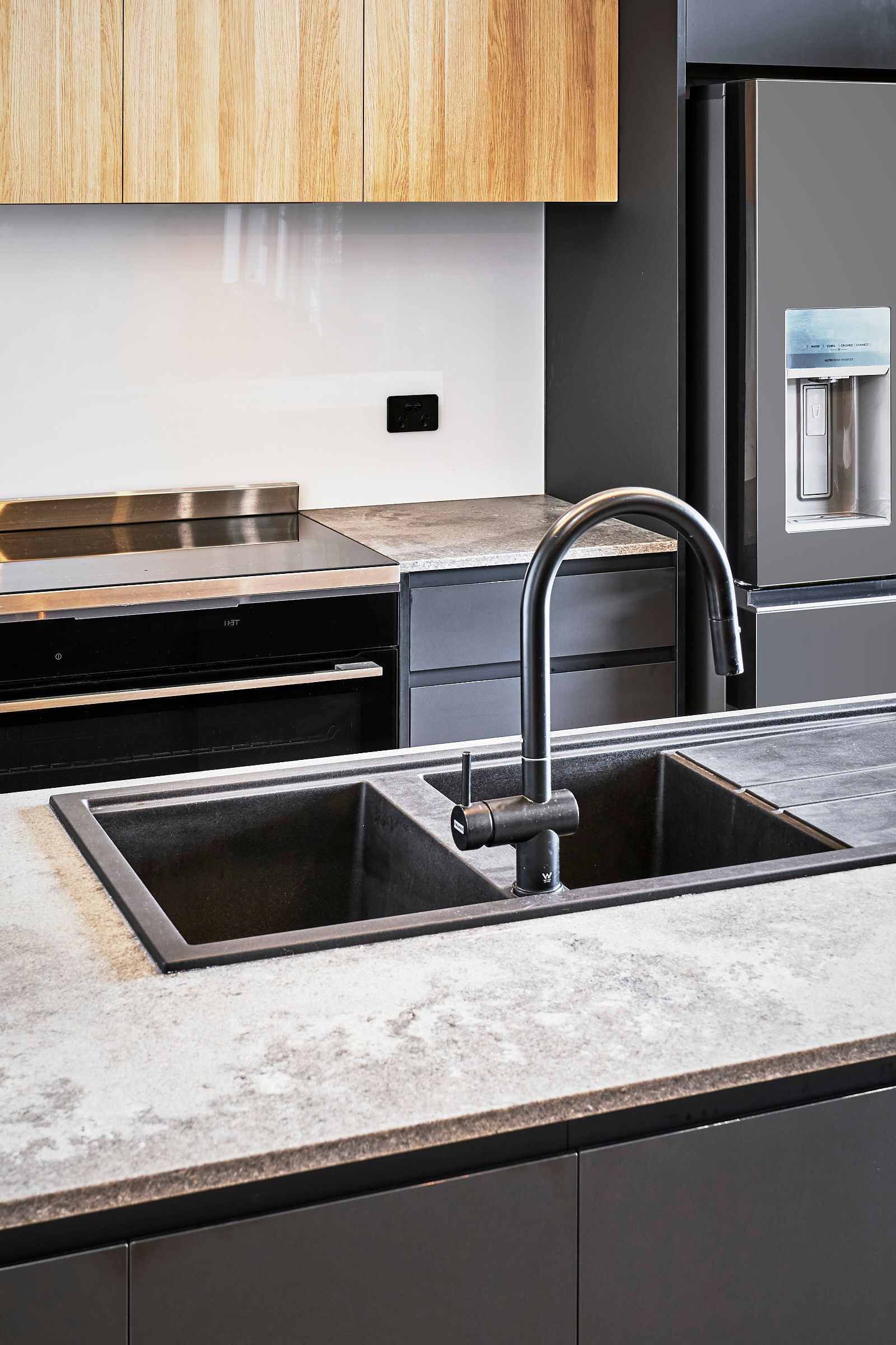 Modern kitchen with a black double sink and faucet on a gray countertop. 