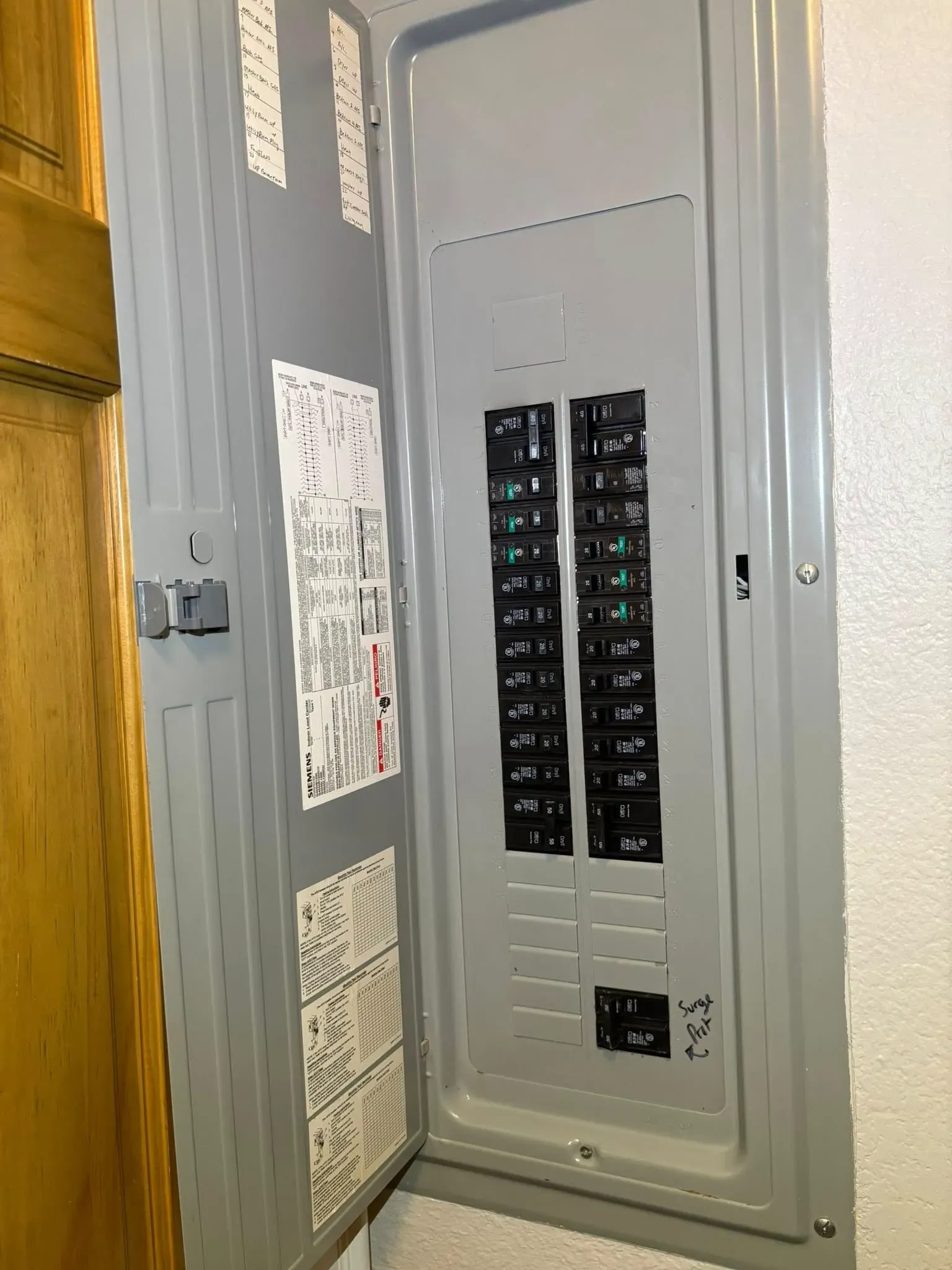 Open electrical breaker panel with rows of switches in a gray metal cabinet