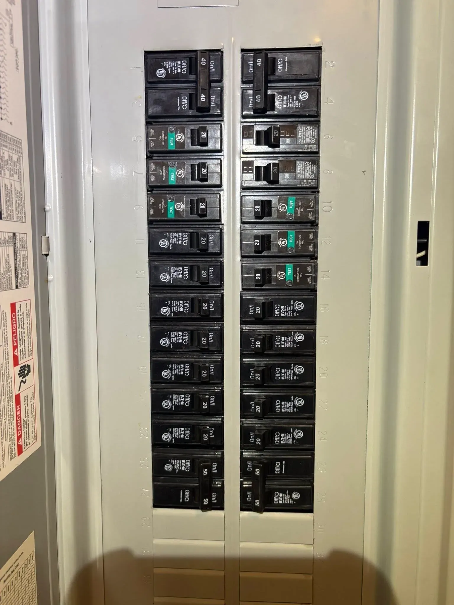 Open electrical breaker panel with rows of black switches and a few lit green indicators
