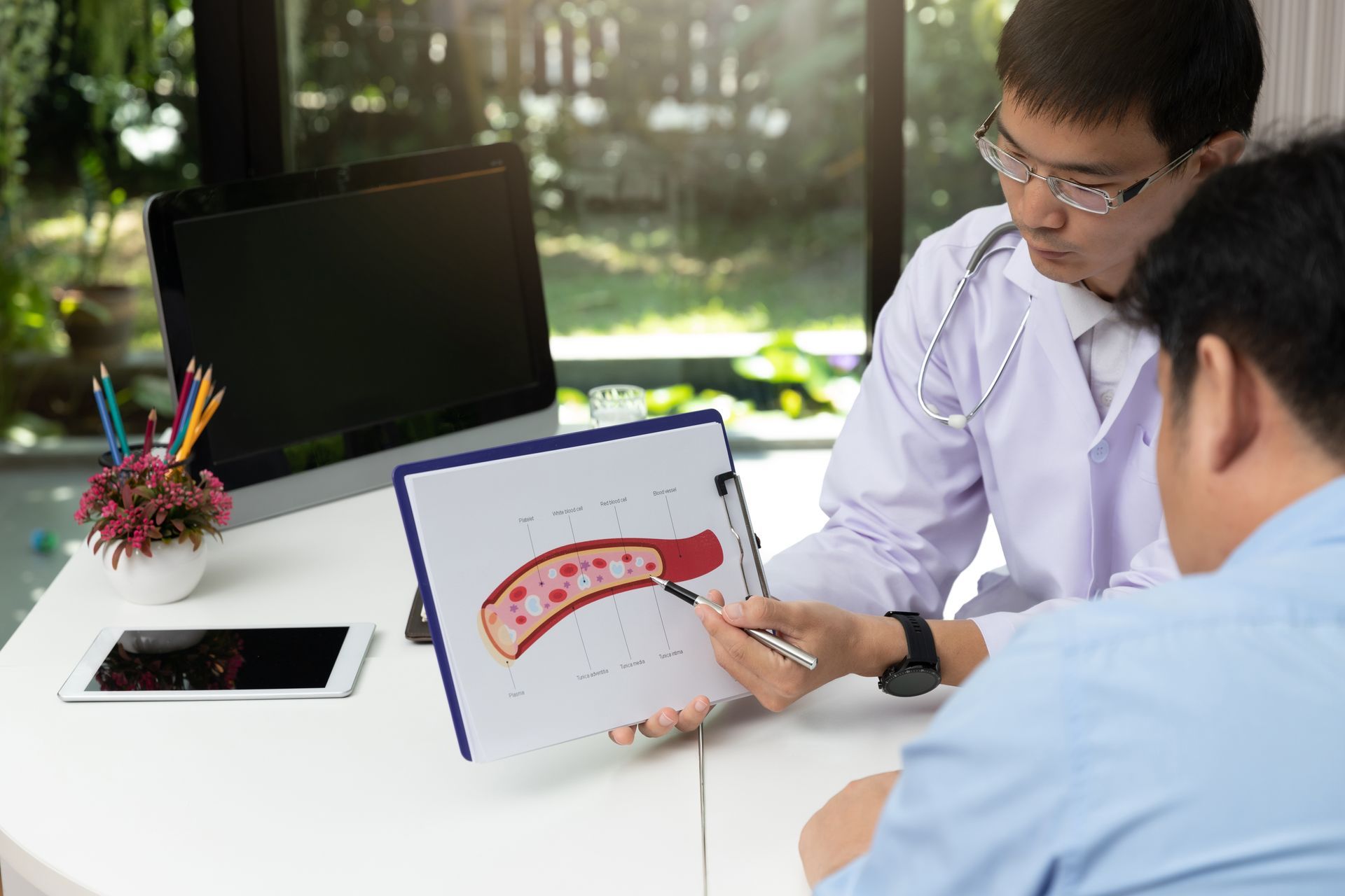 A doctor is explaining a diagram of a blood vessel to a patient. A doctor is explaining a diagram of a blood vessel to a patient.
