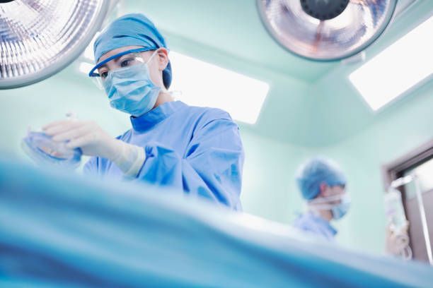 Surgeons in blue scrubs and masks performing surgery in a hospital operating room.