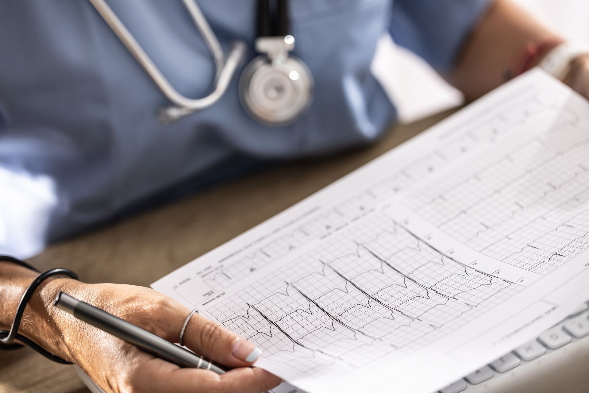 Doctor reviewing electrocardiogram printout while holding pen during evaluation. Doctor reviewing electrocardiogram printout while holding pen during evaluation.