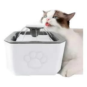 Gato lamiendo una fuente de agua blanca para mascotas con tapa de acero inoxidable.