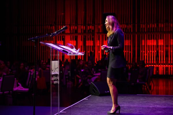 A woman is standing at a podium giving a speech in front of a crowd.