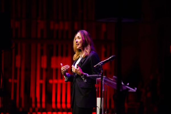 A woman is standing at a podium giving a speech on a stage.
