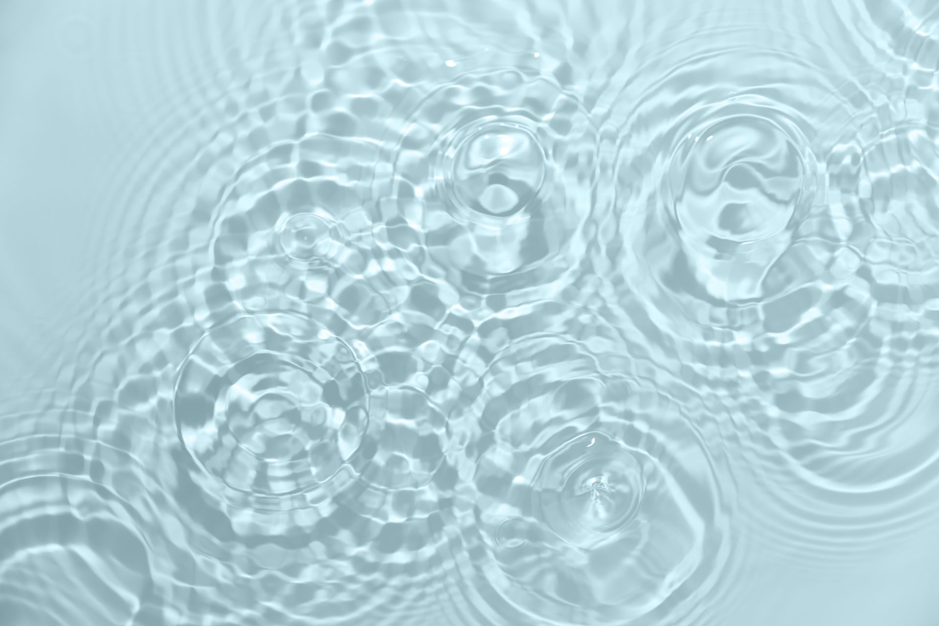 Light blue water surface with overlapping ripples and concentric splash rings