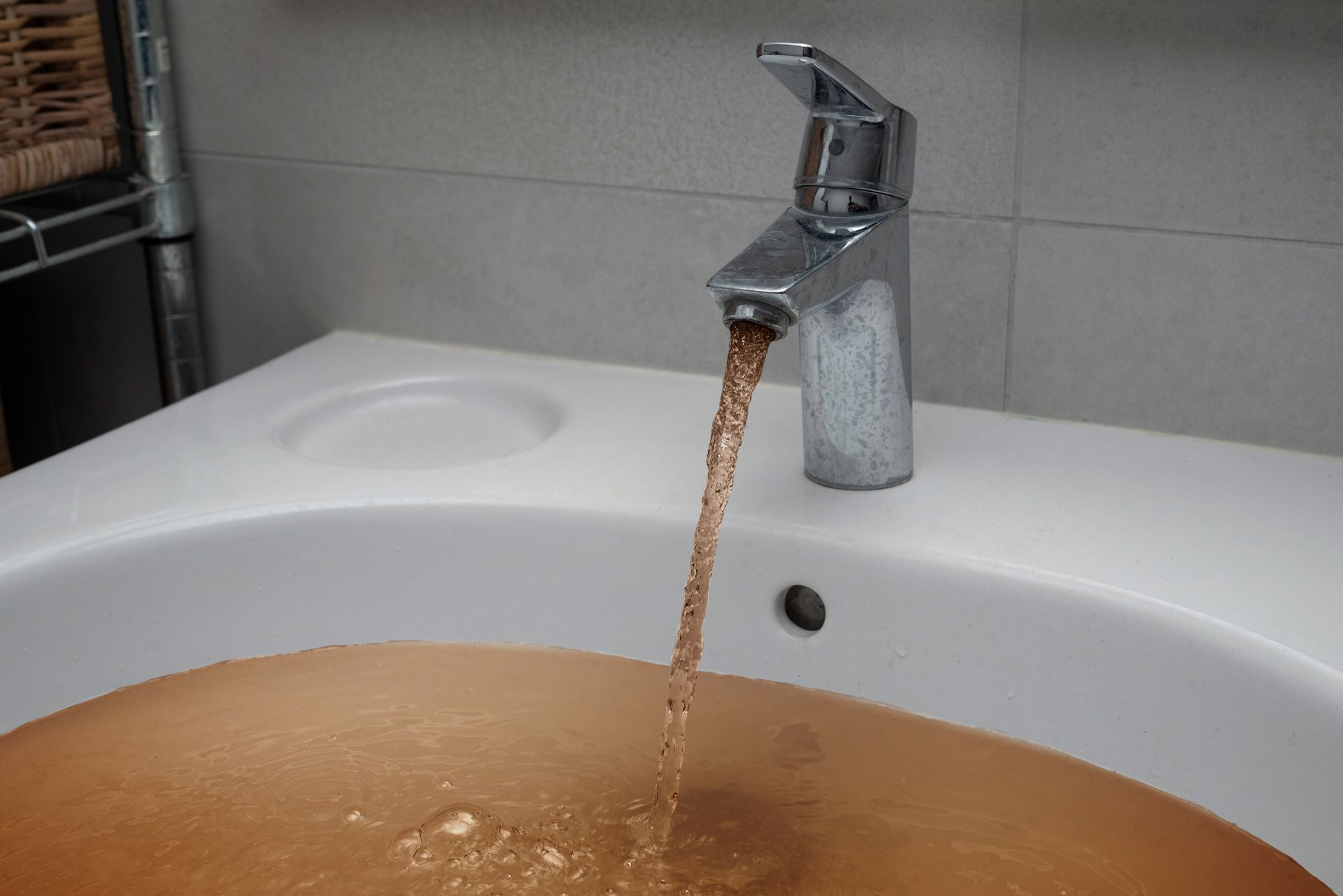 Bathroom sink overflowing with brown water from the faucet
