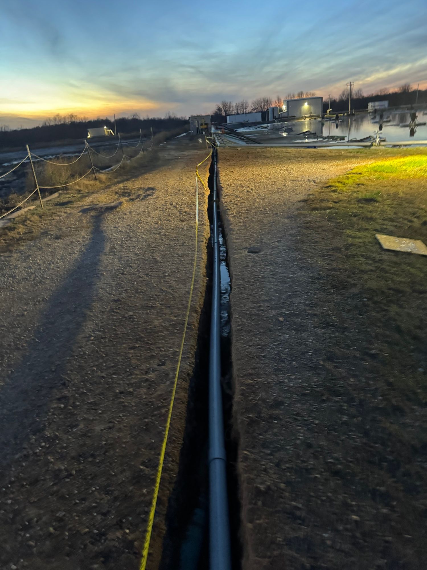 A person is standing next to a pipe in the dirt.