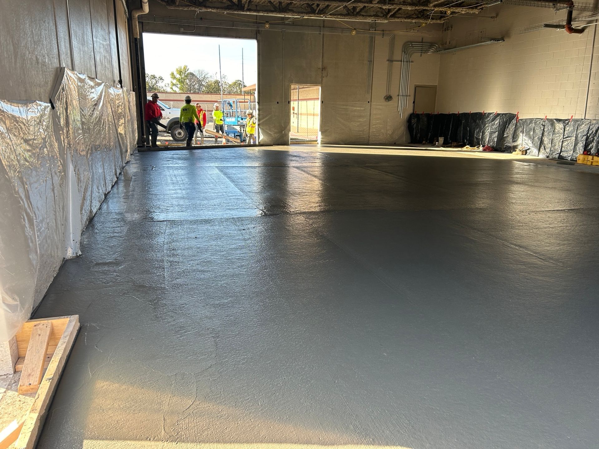 A large empty warehouse with a concrete floor being poured.