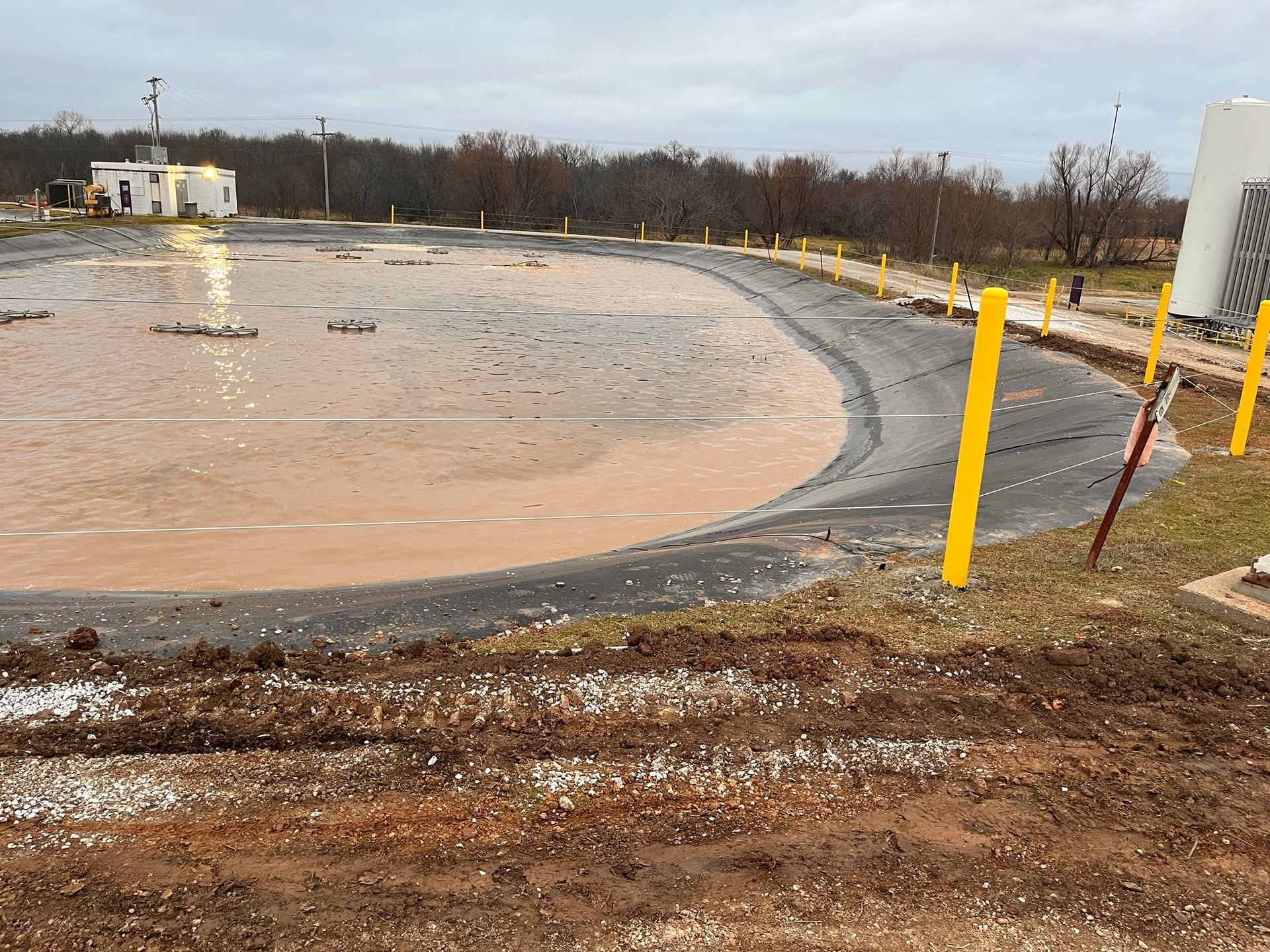 A dirt track with yellow poles and a building in the background.