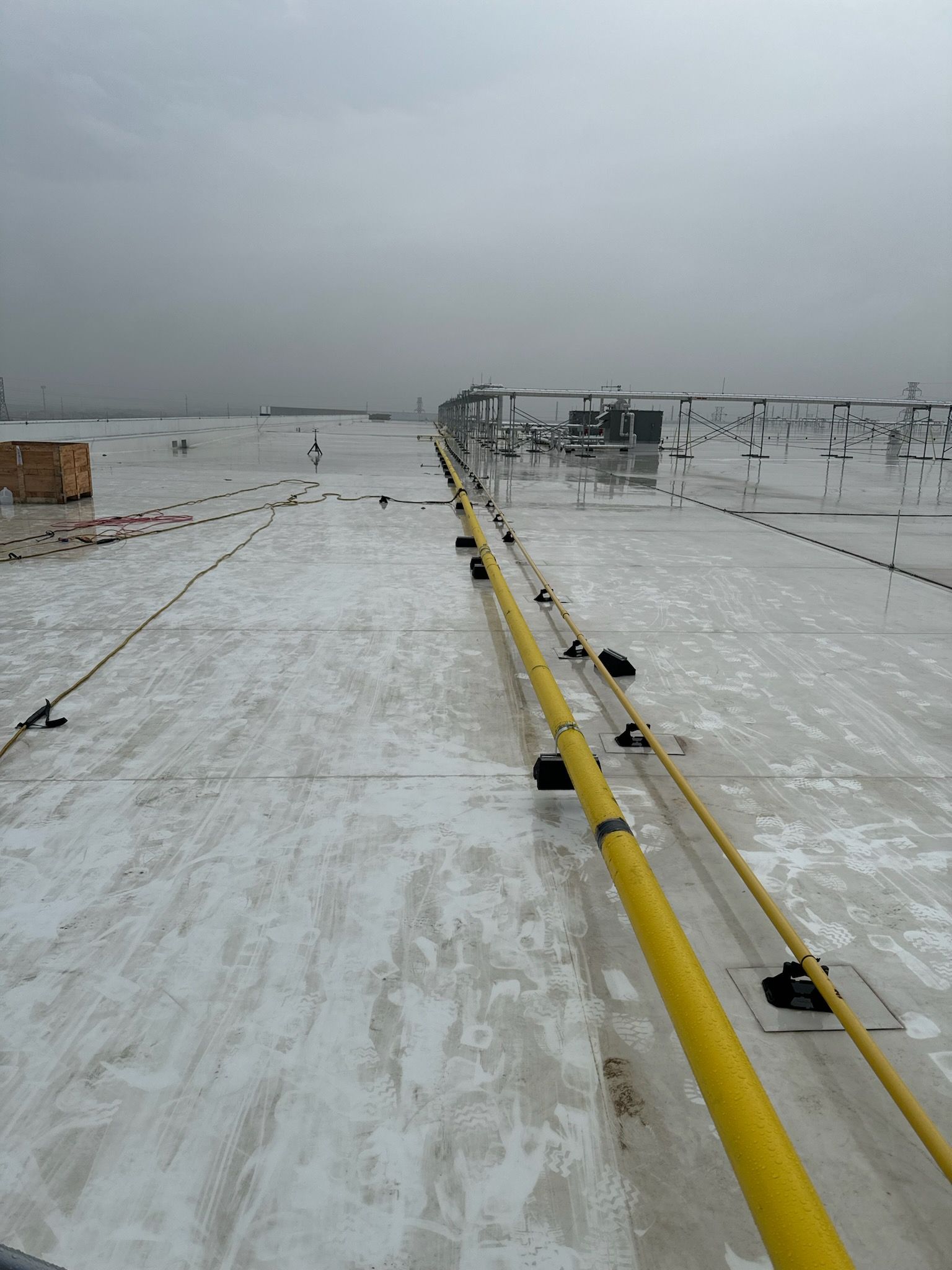 A snowy roof with a yellow pipe on it.