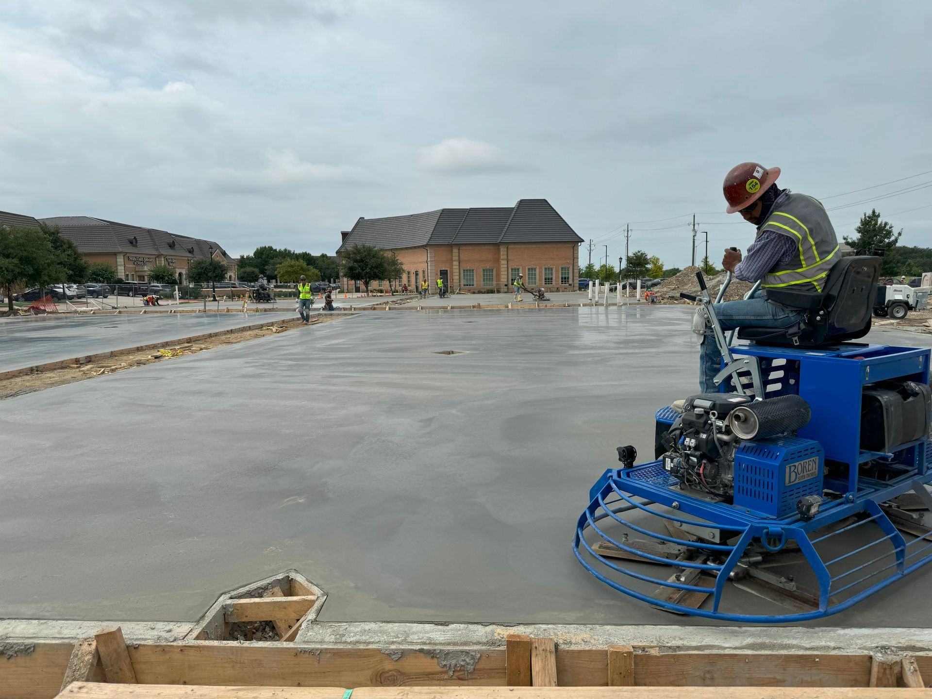 A construction worker is riding a machine on a concrete floor.