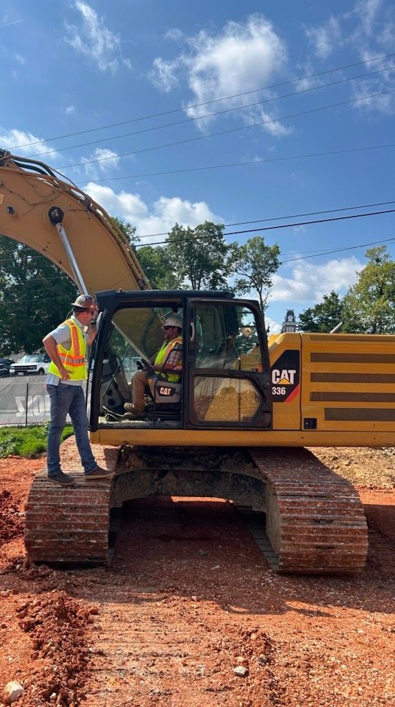 A man is standing next to a large excavator on a construction site.