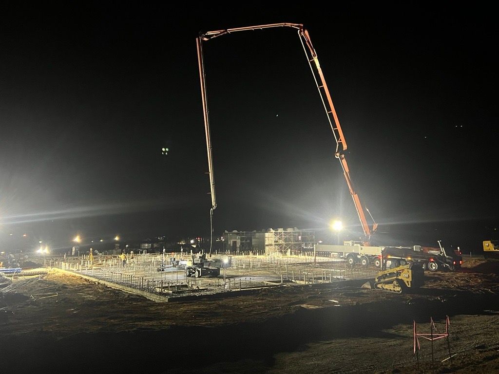A construction site at night with a large crane in the foreground