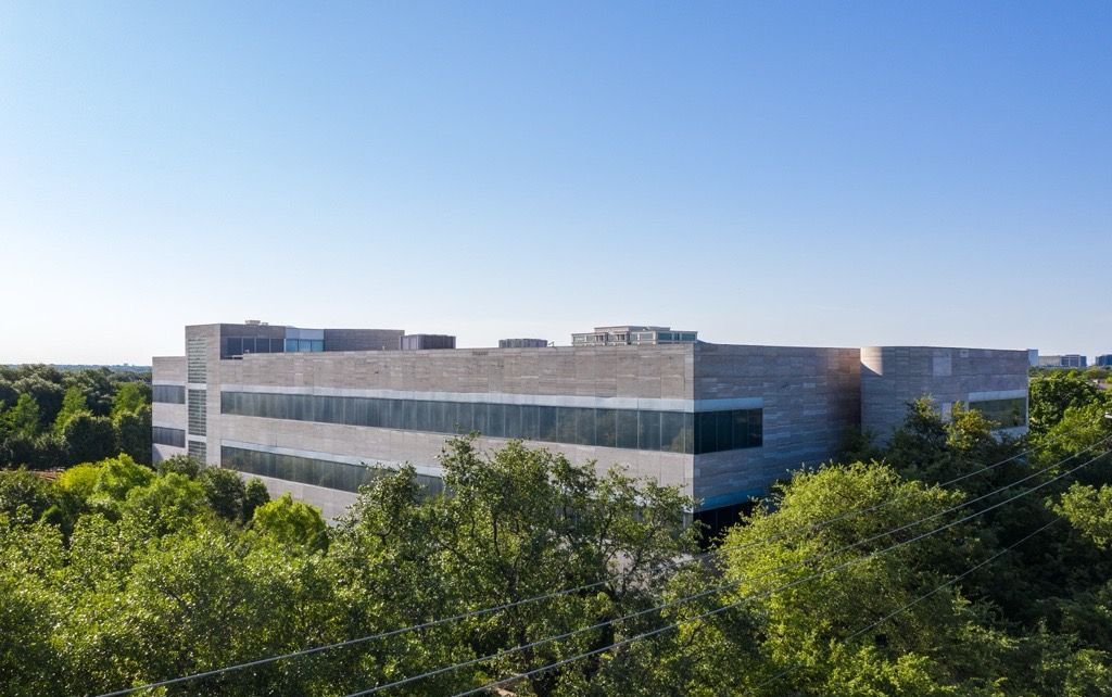 An aerial view of a large building surrounded by trees on a sunny day.