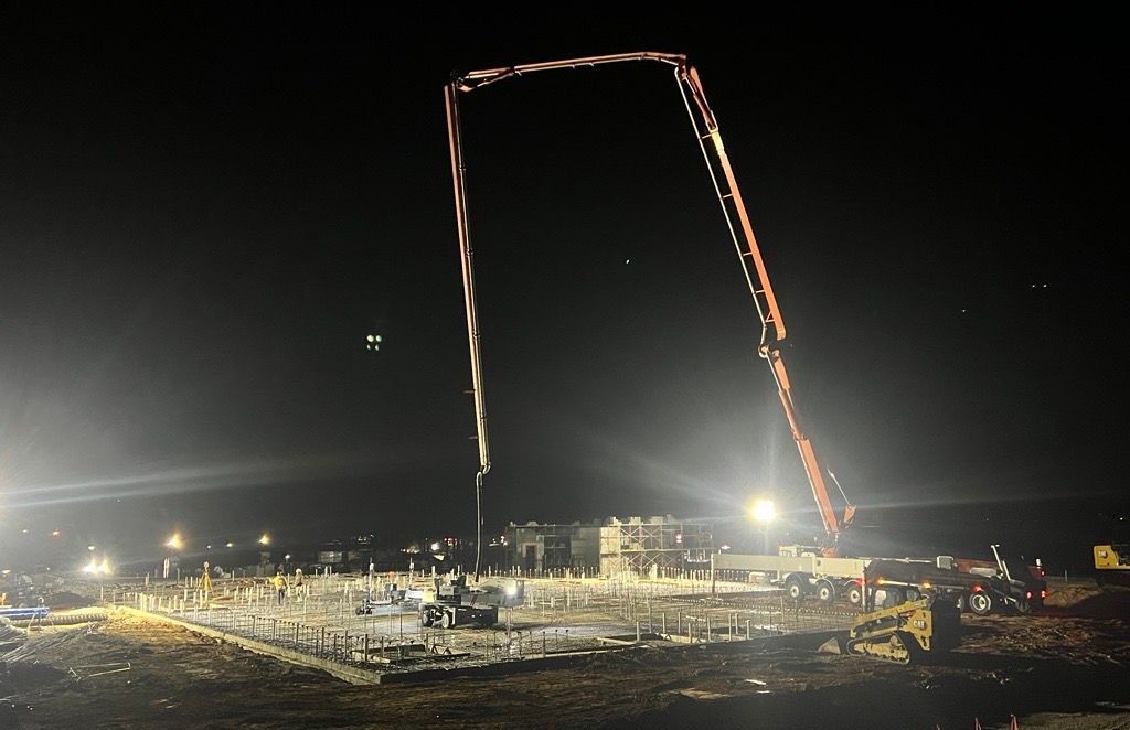 A construction site at night with a crane in the foreground