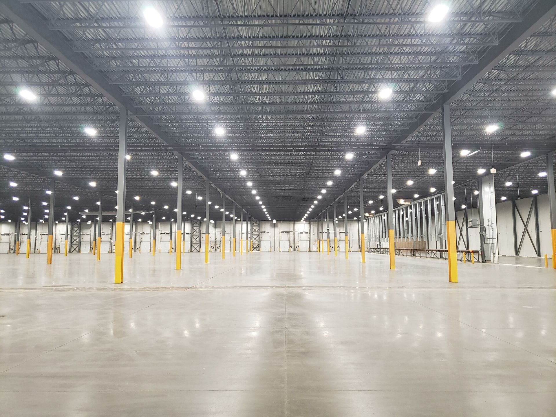 A large empty warehouse with lots of lights on the ceiling.