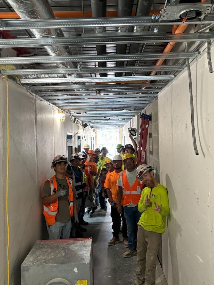 A group of construction workers are standing in a hallway.